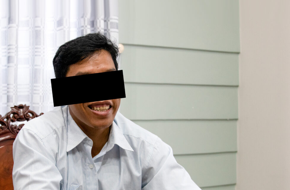 Vietnam front-line worker smiles and sits in chair