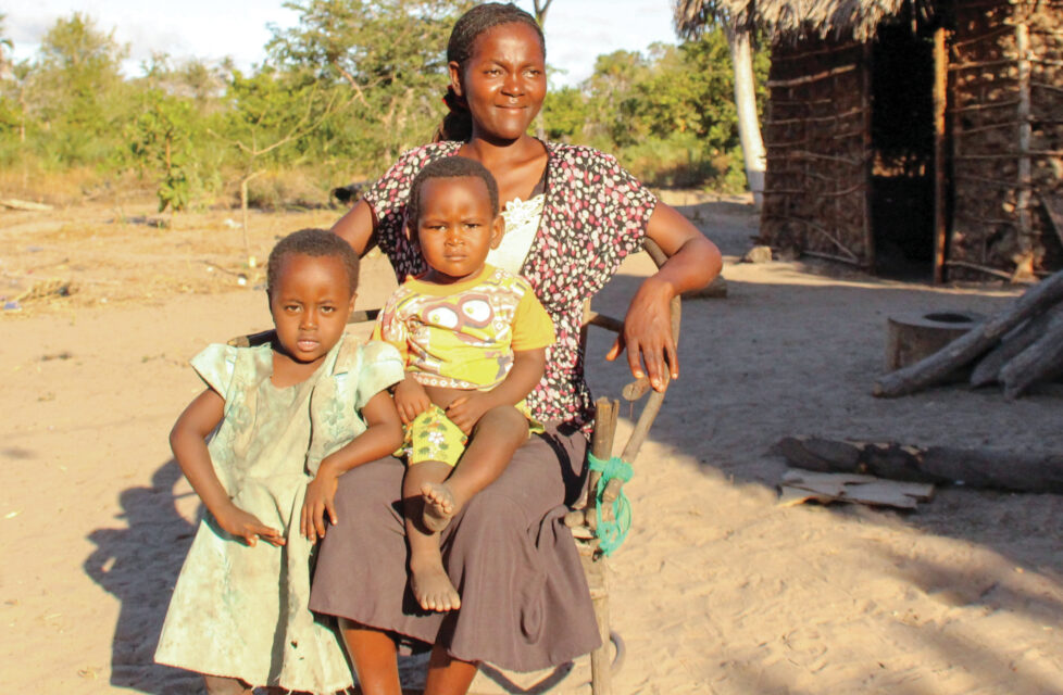Mother and two children sitting in front of their hut